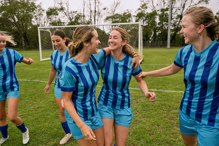 A group of community soccer players (a local team) are supporting and hugging each other