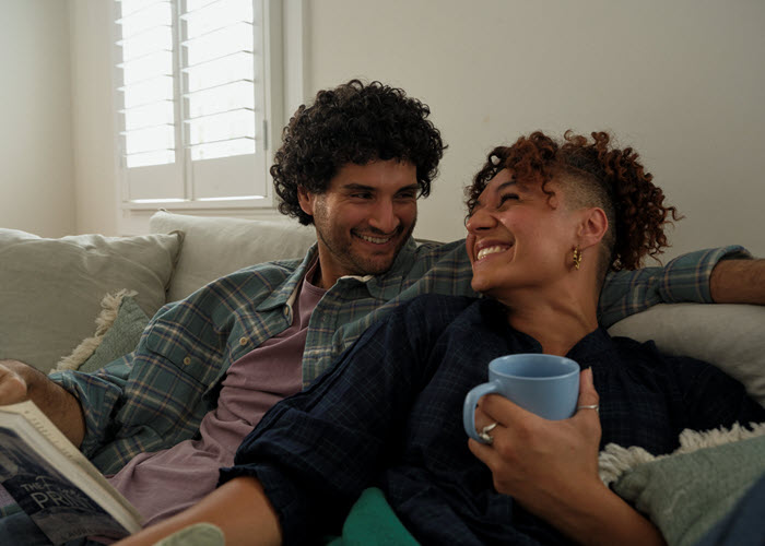 Couple sitting on the couch with coffee mug and book